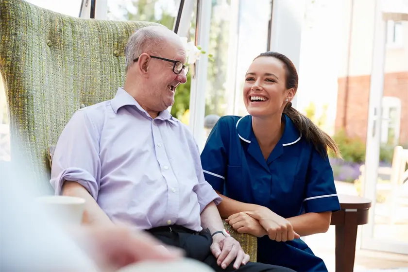 An old man and a care worker smiling